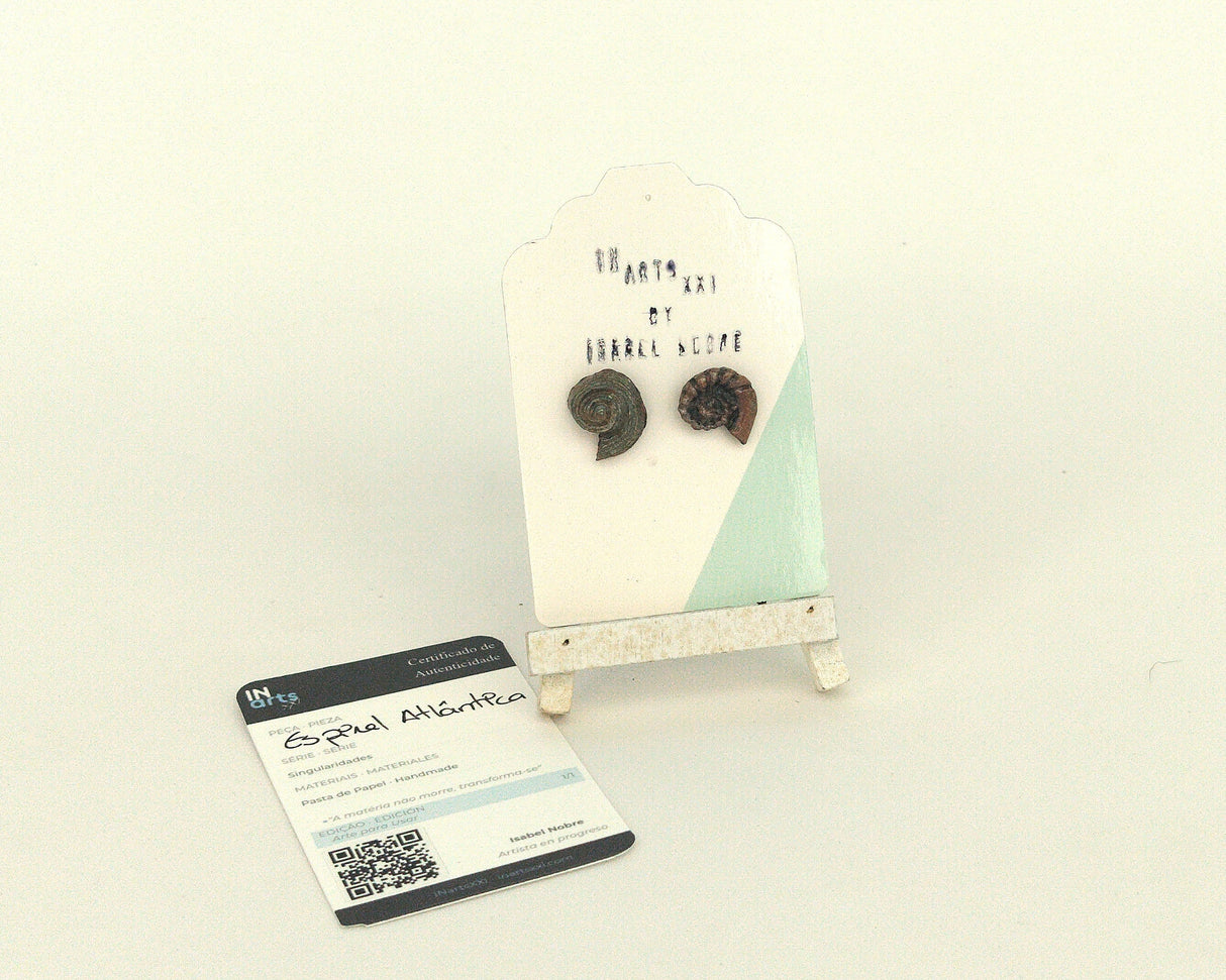 Pendientes de botón artesanales con forma de fósiles de caracol marino modelo Espiral Atlántica de la Serie Singularidades por Isabel Nobre, hechos de pasta de papel con certificado de autenticidad.