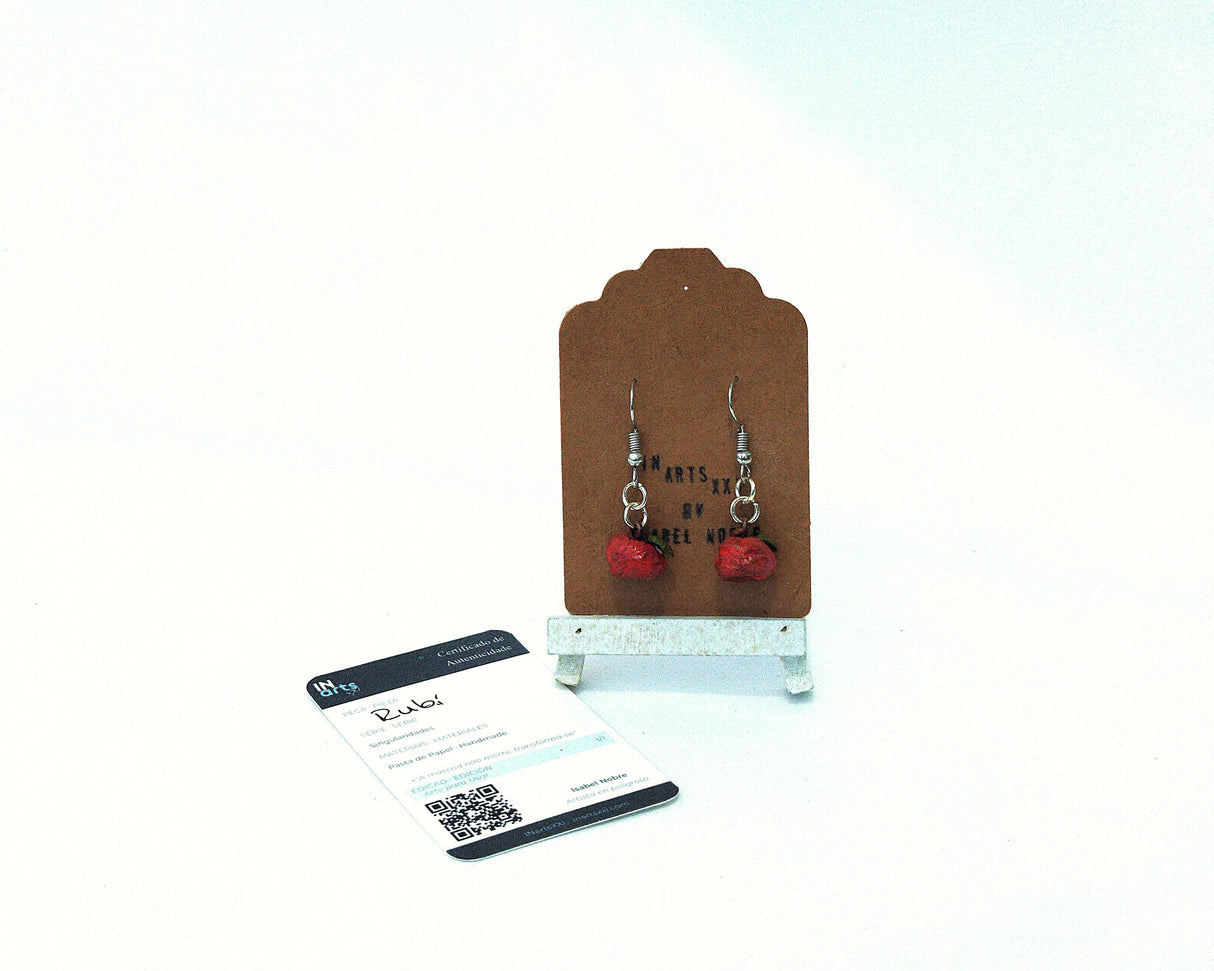 Pendientes de gancho artesanales rojos modelo Rubi de la Serie Singularidades por Isabel Nobre, modelados en pasta de papel con certificado de autenticidad sobre expositor blanco.