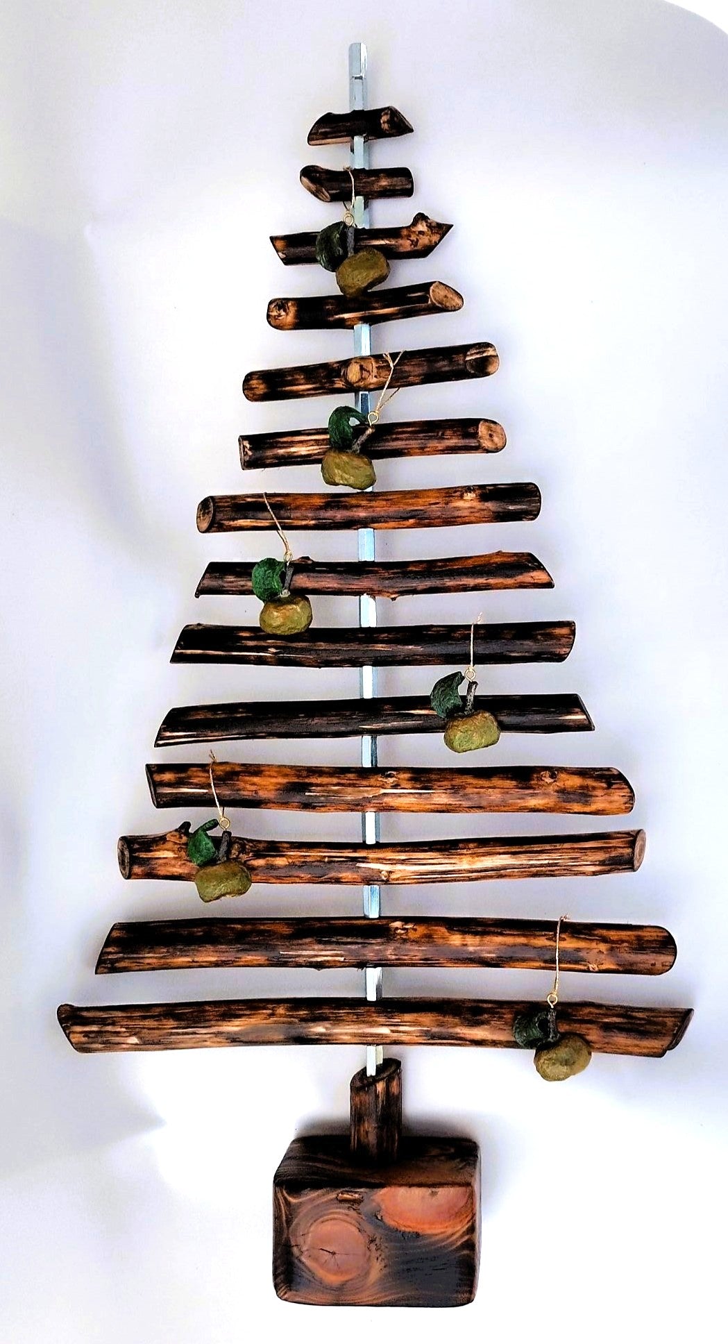 Escultura de árbol hecha con ramas carbonizadas mediante la técnica Yakisugi y decorada con manzanas Ibarbi de pasta de papel, de la Serie Elemental por Isabel Nobre