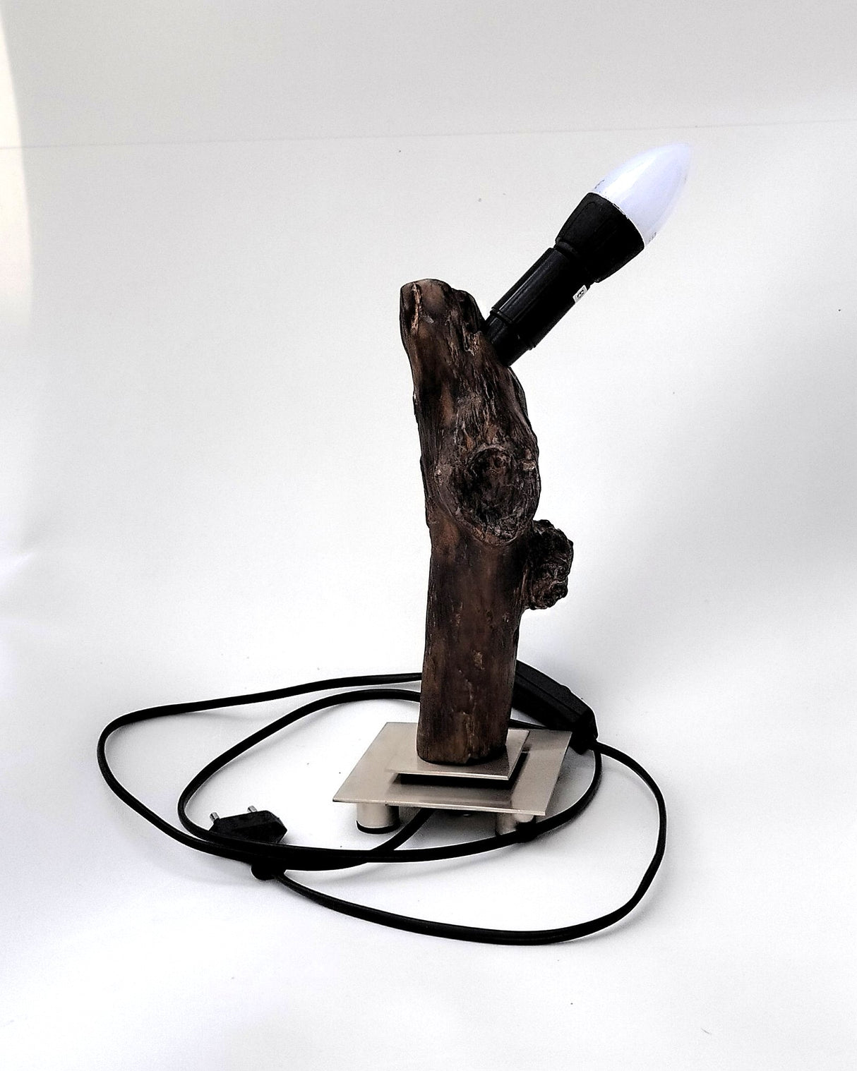 Lámpara de diseño Sentinela con tronco de madera flotante carbonizada Yakisugi sobre base metálica cuadrada de estilo industrial.