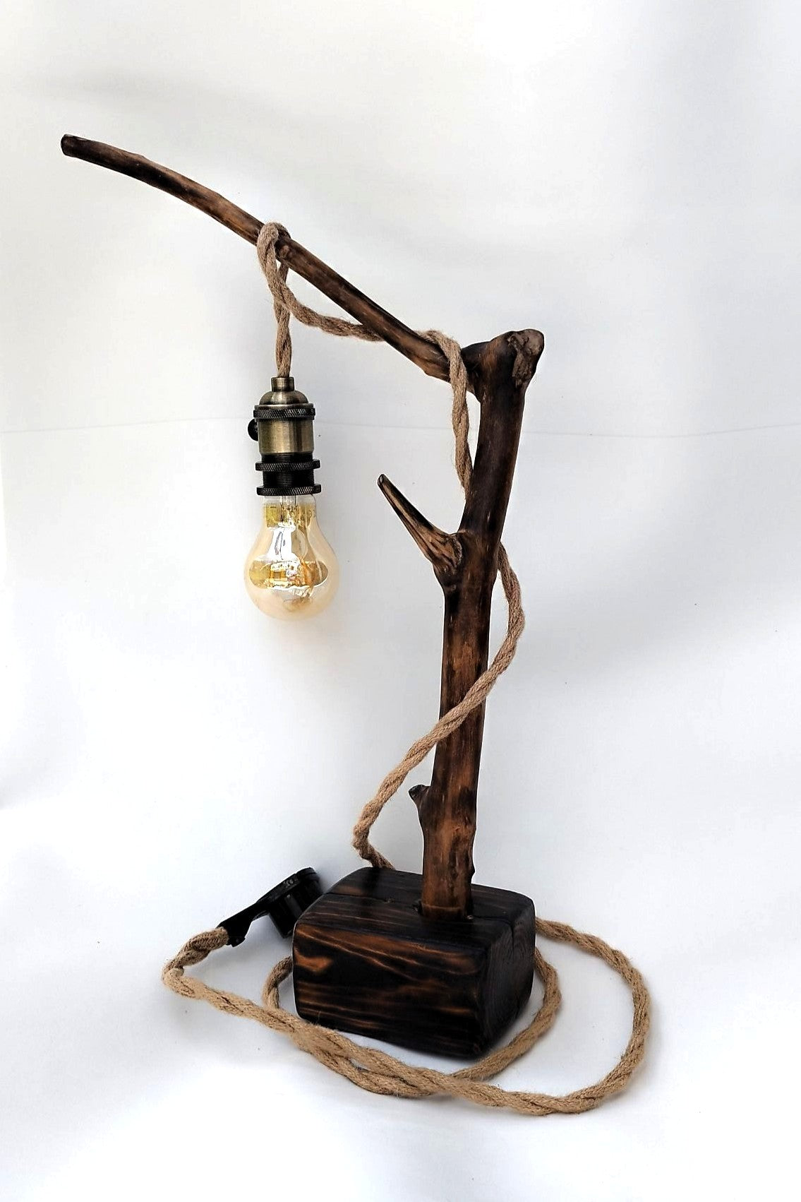 Lámpara de mesa artesanal Raiz de Luz hecha de madera flotante carbonizada Yakisugi y cable de cuerda de yute sobre fondo blanco.