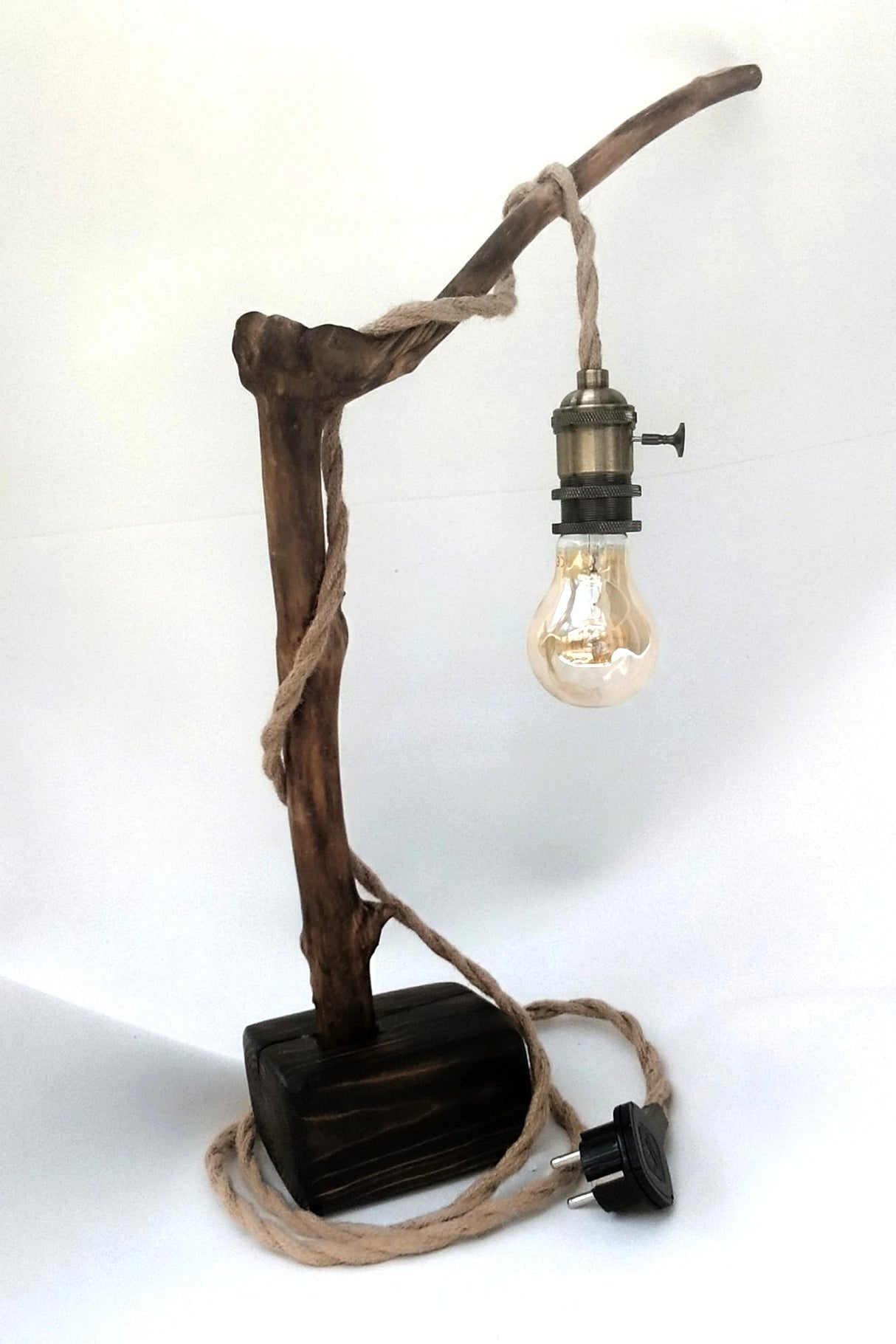Lámpara de mesa artesanal Raiz de Luz hecha de madera flotante carbonizada Yakisugi y cable de cuerda de yute sobre fondo blanco.