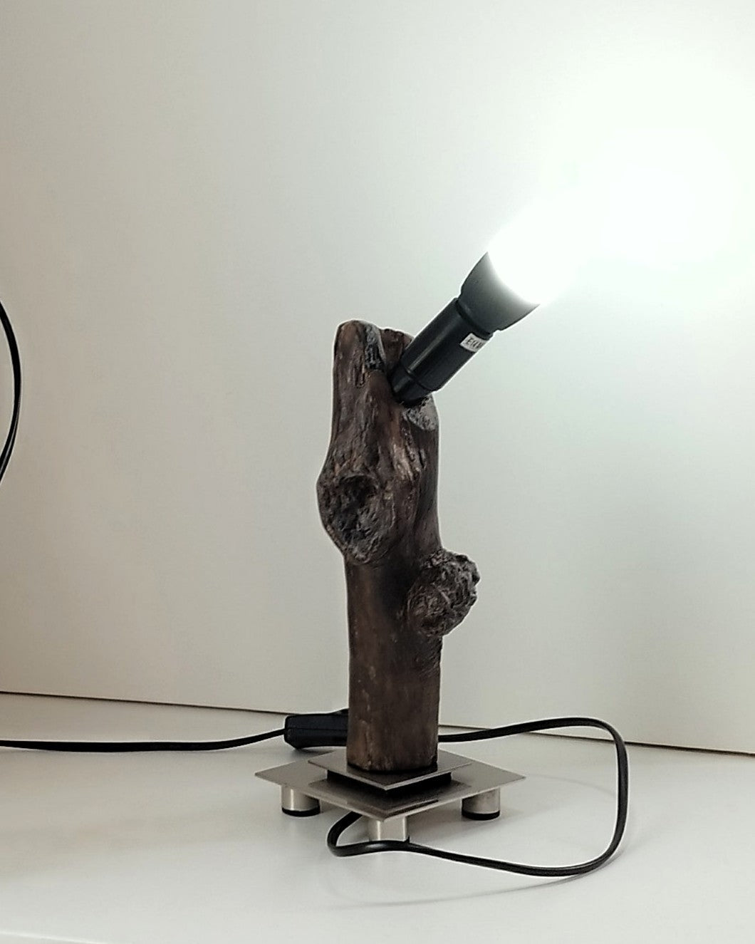  Lámpara de diseño Sentinela con tronco de madera flotante carbonizada Yakisugi sobre base metálica cuadrada de estilo industrial.